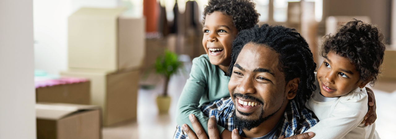 Happy African American kids embracing their single father at new apartment