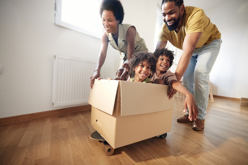 Mother and father pushing two kids in a moving box