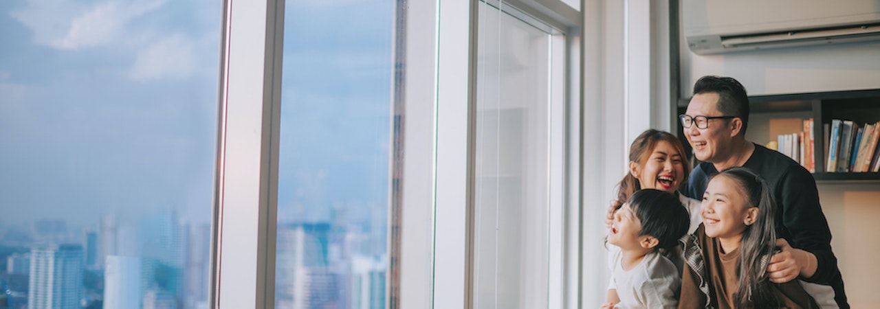 Asian family looking out window of condo
