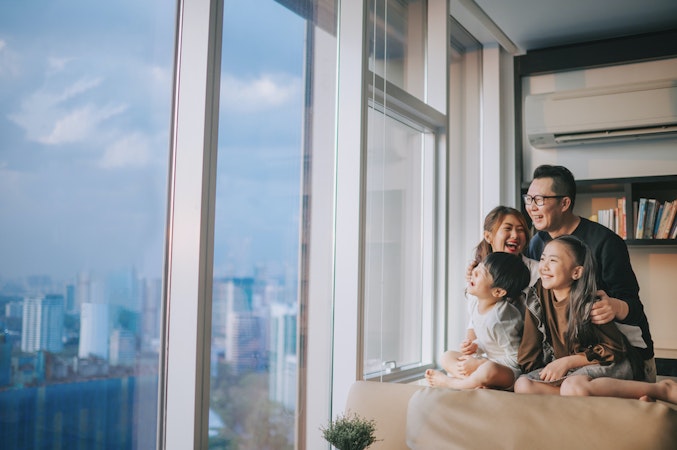 Asian family looking out window of condo