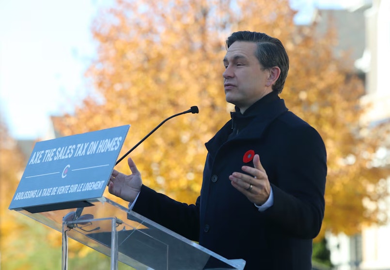 A politician standing behind a lectern outdoors speaking with hands outstretched