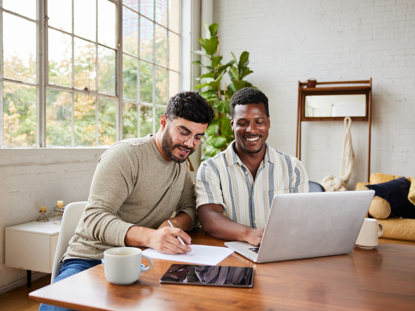 Two men working on a budget with a laptop and a pen an pad of paper