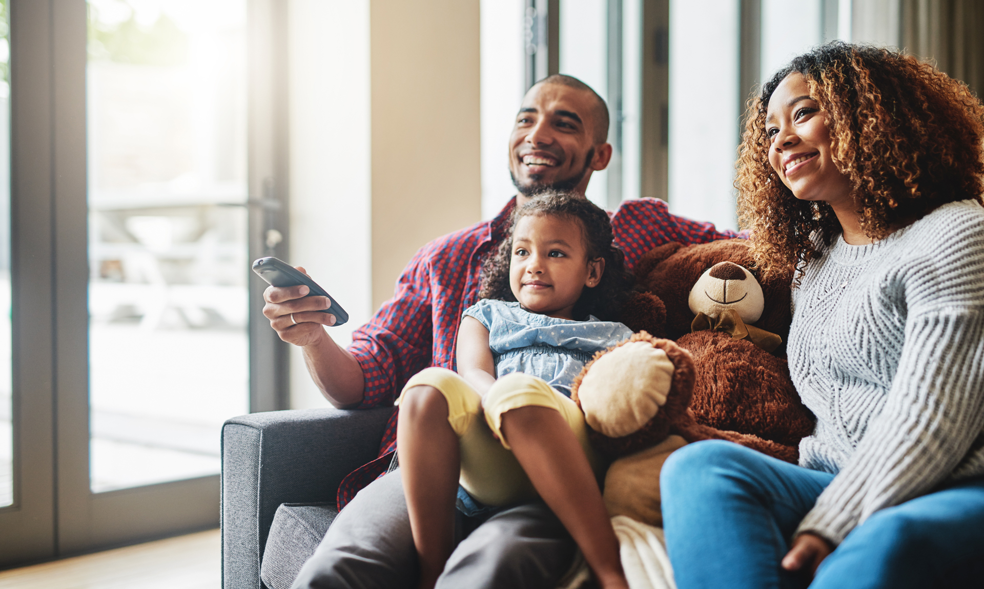Man, woman, and child watching tv on a couch