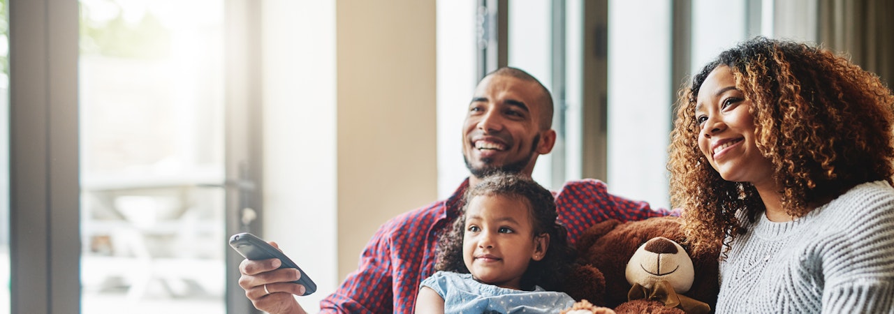 Man, woman, and child watching tv on a couch