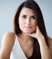 Woman posing and smiling in front of a white background.