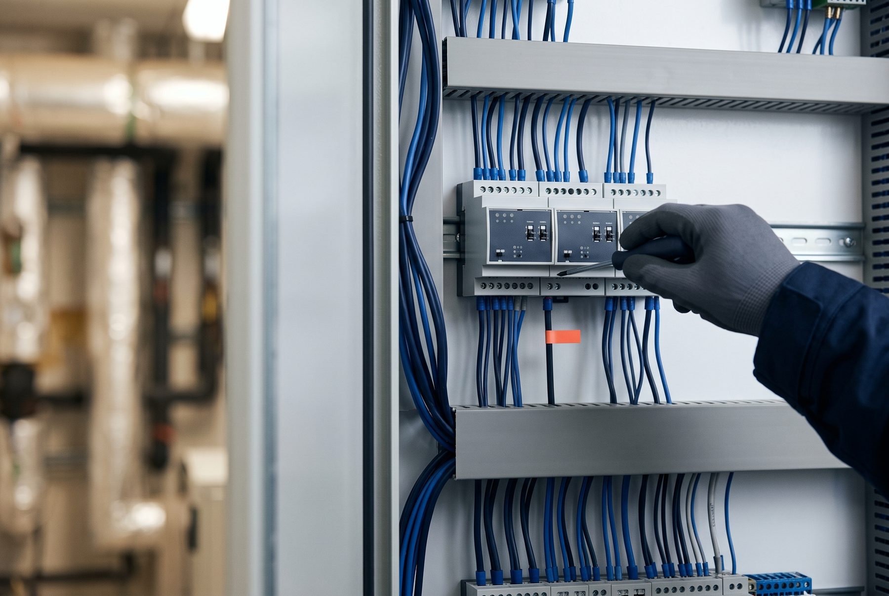 Mano con guante trabajando en un módulo de control de automatización