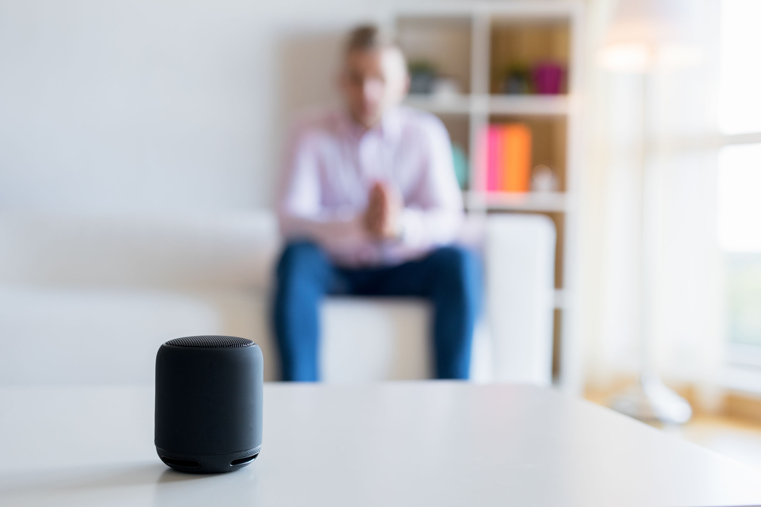 Man talking to virtual assistant smart speaker in living room|Man hand touching to multimedia system with app personal assista|man using internet voice search technology on mobile phone