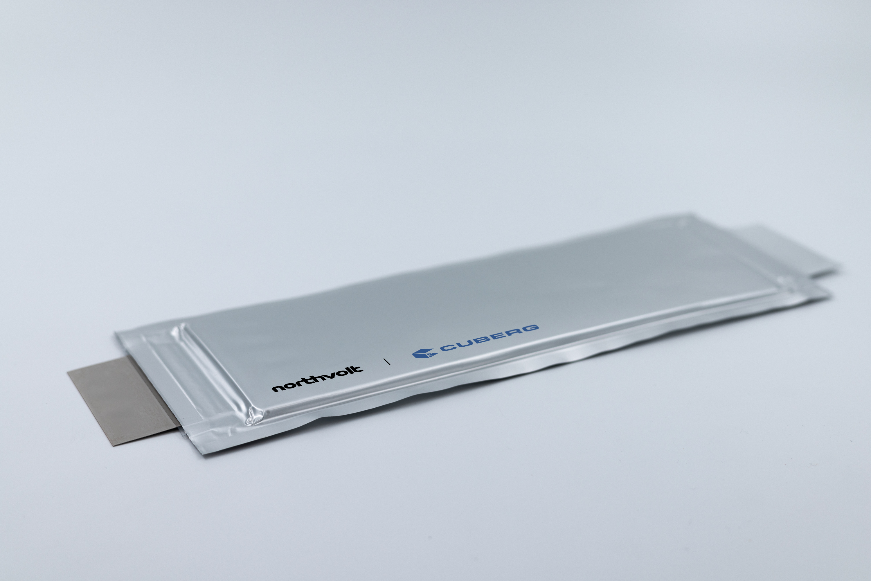 Photo of a metallic silver battery cell with Cuberg and Northvolt corporate logos.