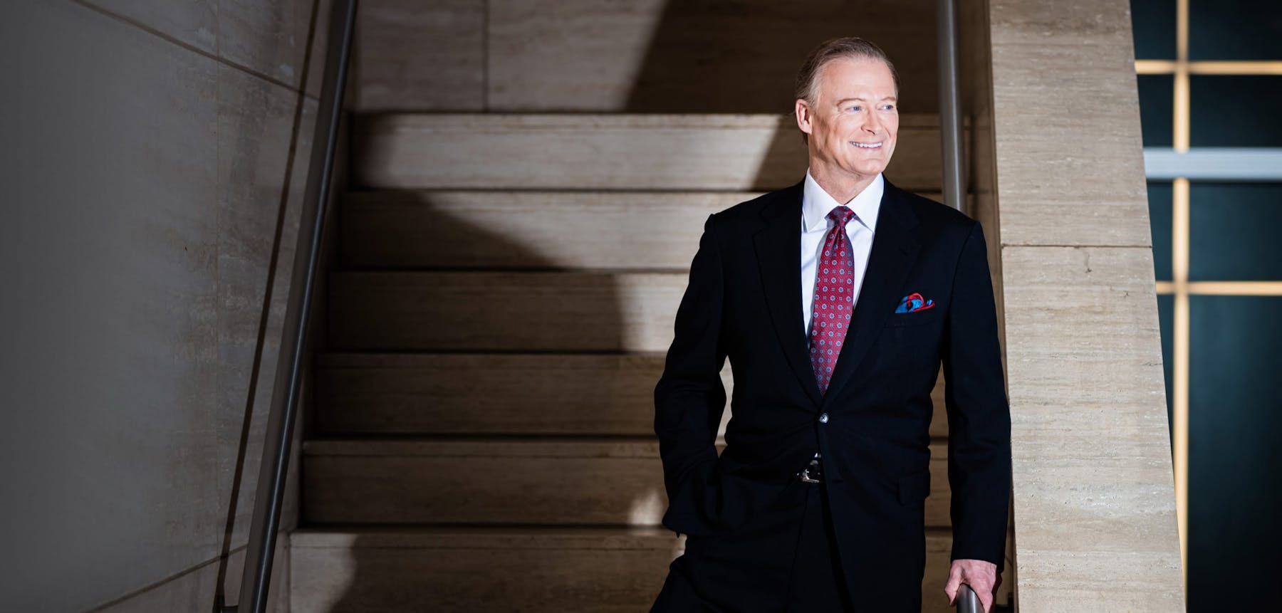 Dr. Henry smiling in a suit on a stairwell