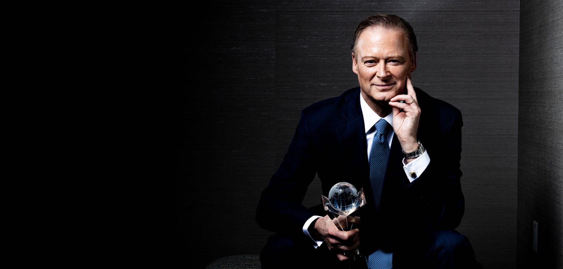 Dr. Henry smiling in a suit while holding an award