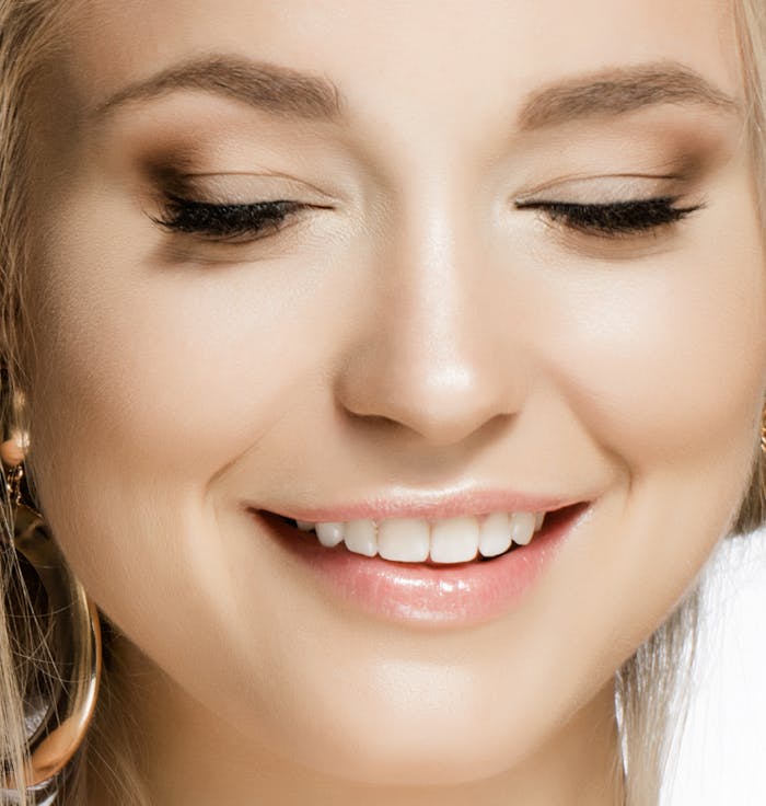Beautiful woman closing her eyes and smiling after revision rhinoplasty surgery