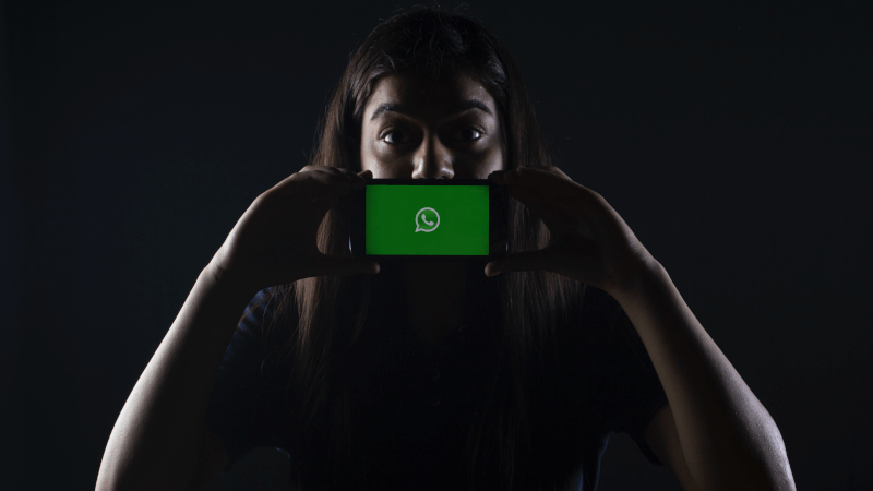 a person holding a phone with the WhatsApp logo on the screen