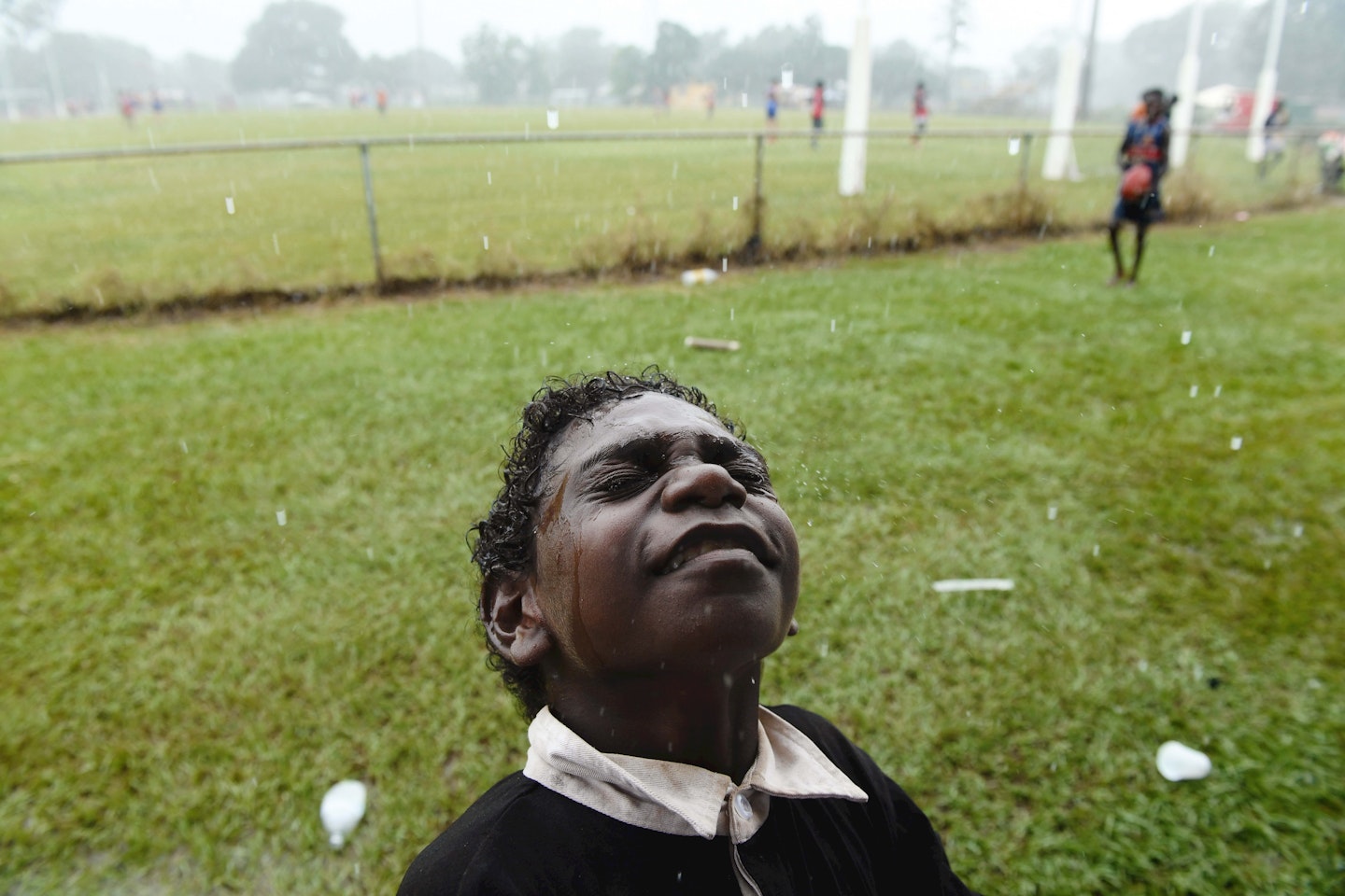 A young football fan feels the rain on his face minutes before kick-off for the Tiwi Islands grand final – the muddiest game of football.
