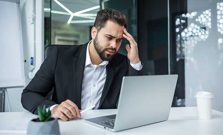 Employee looking at their screen with hands on their head and a worried look
