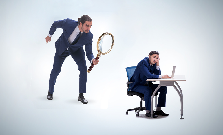 An employee using their computer and right across them, their manager is watching them