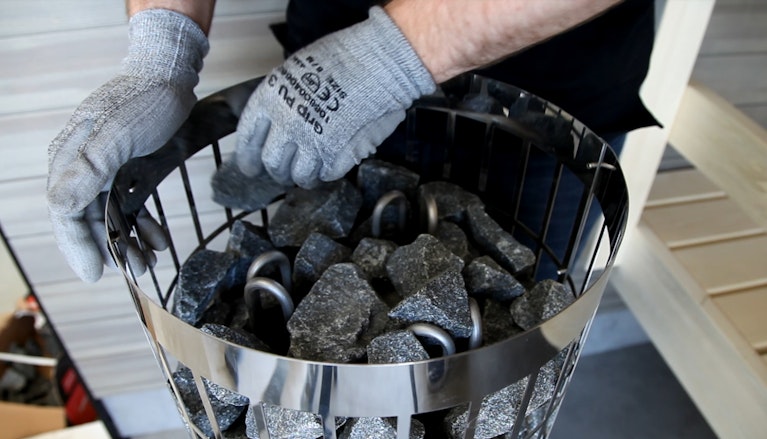 man assembling sauna stones to heater