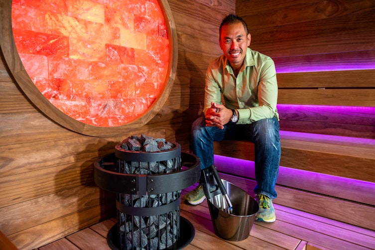 man sitting inside of sauna looking into camera