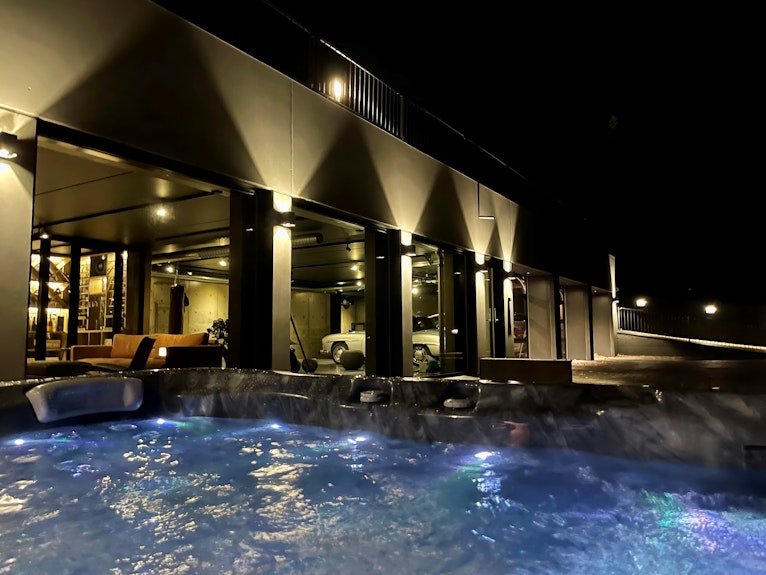 Outdoor jacuzzi with sauna mancave view in background