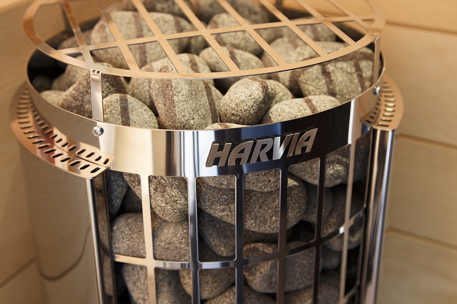Harvia Cilindro sauna heater installed in a wooden sauna room showing integrated safety sheath