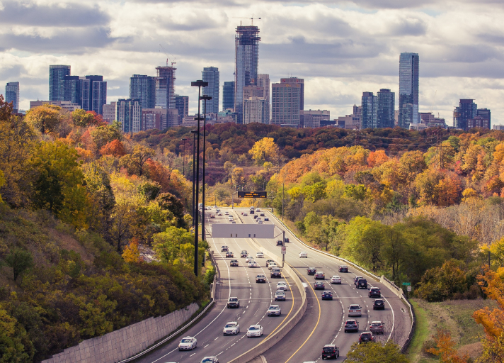 An aerial photo of passing vehicles on a highway leading to and from a city in the distance