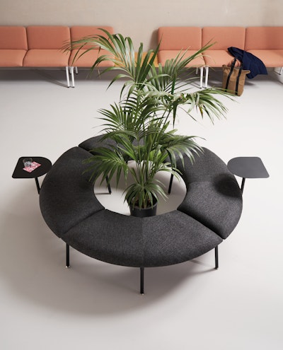 Mega armchair with built-in coffee tables arranged around a plant