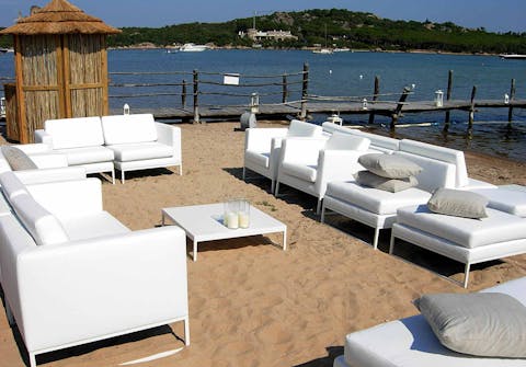 Divani Quinti di varie misure in spiaggia Divani Quinti con sopra dei cuscini disposti intorno ad un tavolino in spiaggia