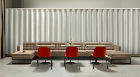 Vogue modular armchairs and sofas A four-person sectional sofa in front of three highly stackable conference room chairs.