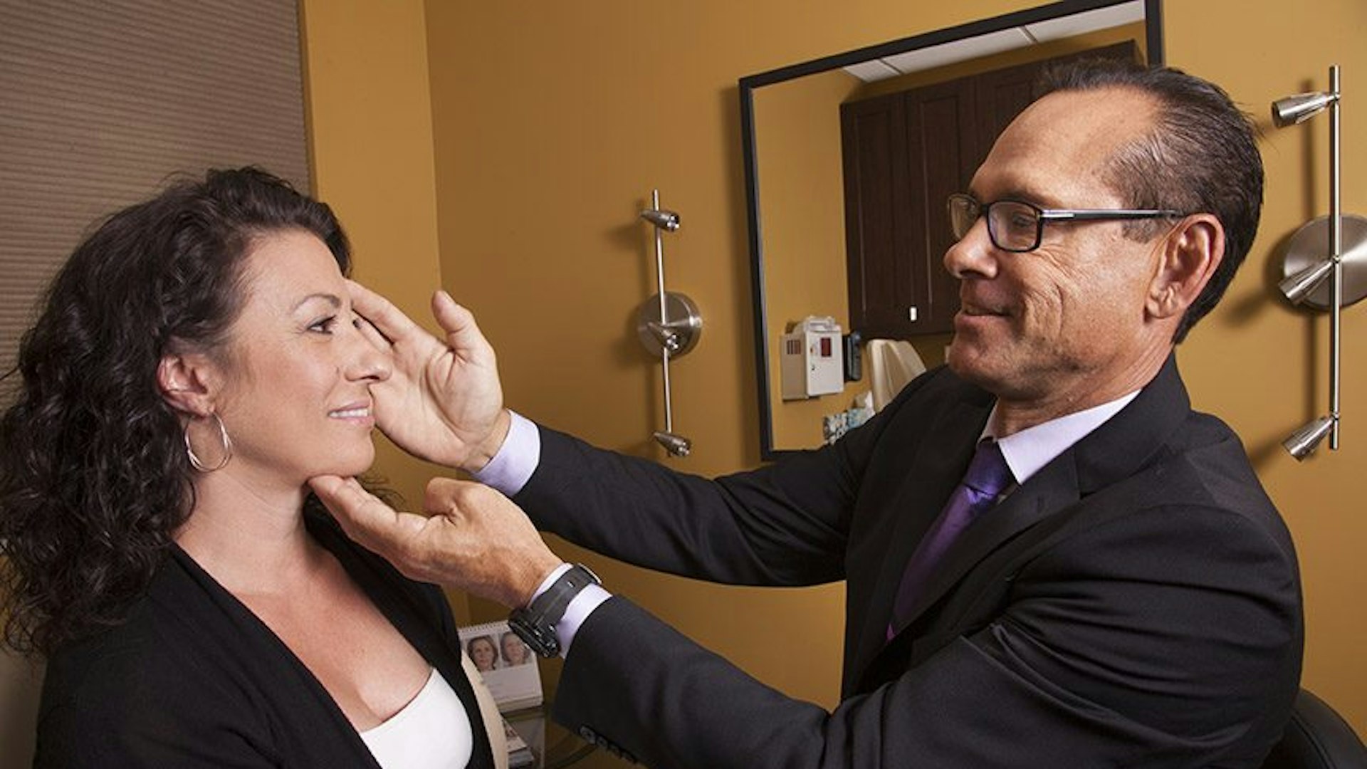 Dr. George Orloff assessing the face of a female patient in the exam room