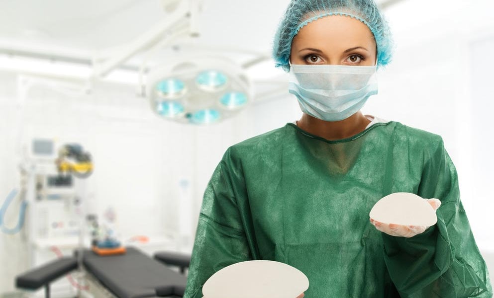 Plastic surgeon holding different size silicon breast implants in a surgery room