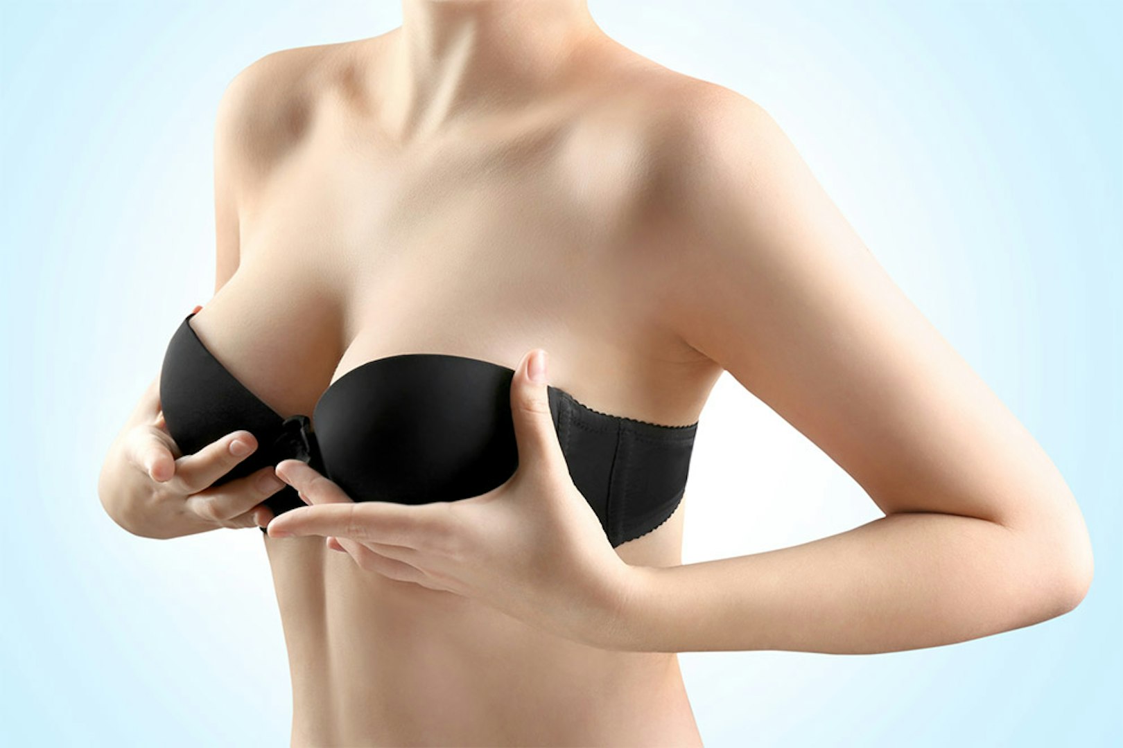 woman wearing black bra holding her breast
