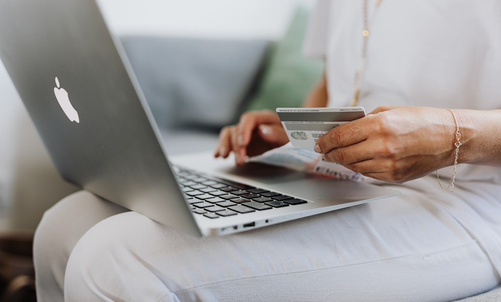 Woman with a laptop holding a. credit card in her hand.