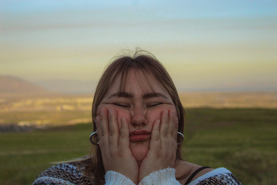 Rachael Jenkins holding her face, with stunning Utah landscape behind