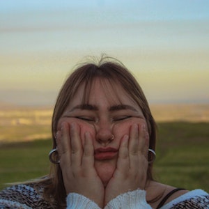 Rachael Jenkins holding her face, with stunning Utah landscape behind