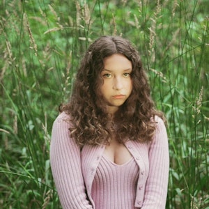 Lia Pappas-Kemps sat in a field of long grass