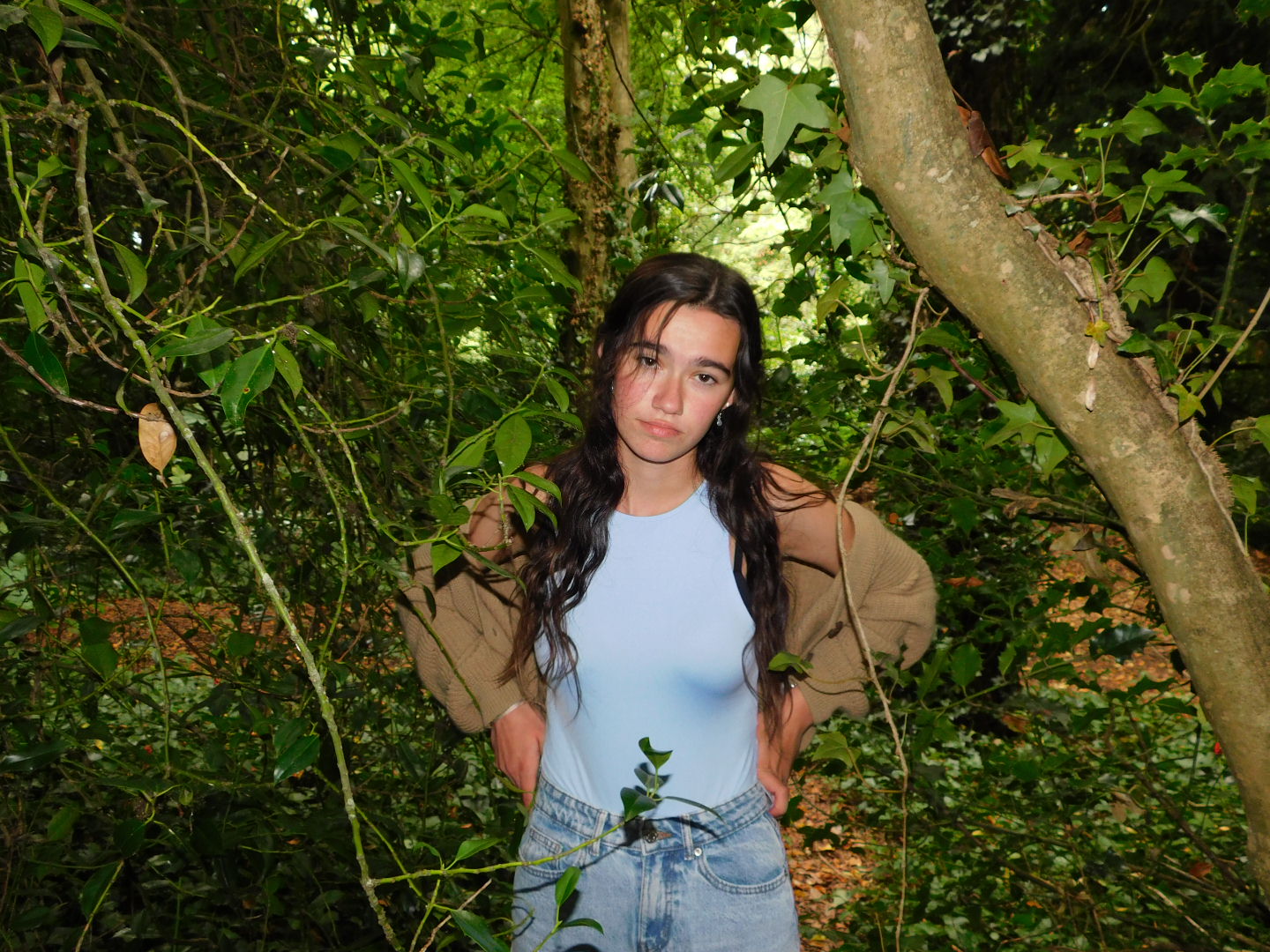 Annika standing in a wooded area with her hands on her hips looking into the camera