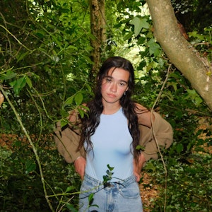Annika standing in a wooded area with her hands on her hips looking into the camera