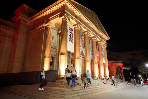 People on the steps of a large sandstone building with columns