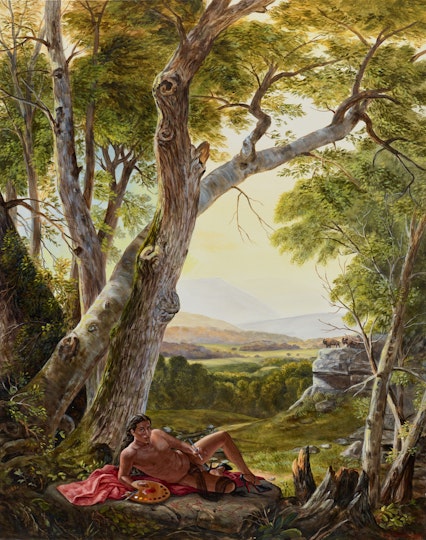 A person lies on their side under a large tree, with views of fields and hills in the background.