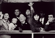 A black and white photograph of several people waving from a ship.