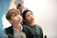 Two primary school children looking up at an artwork