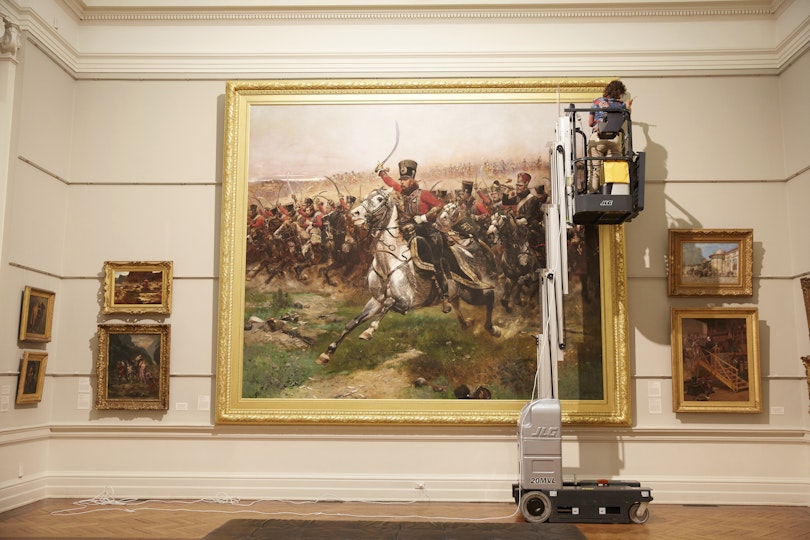 Conservator Melissa Harvey dusts the 1891 Édouard Detaille painting Vive L'Empereur! in the Old Courts.
