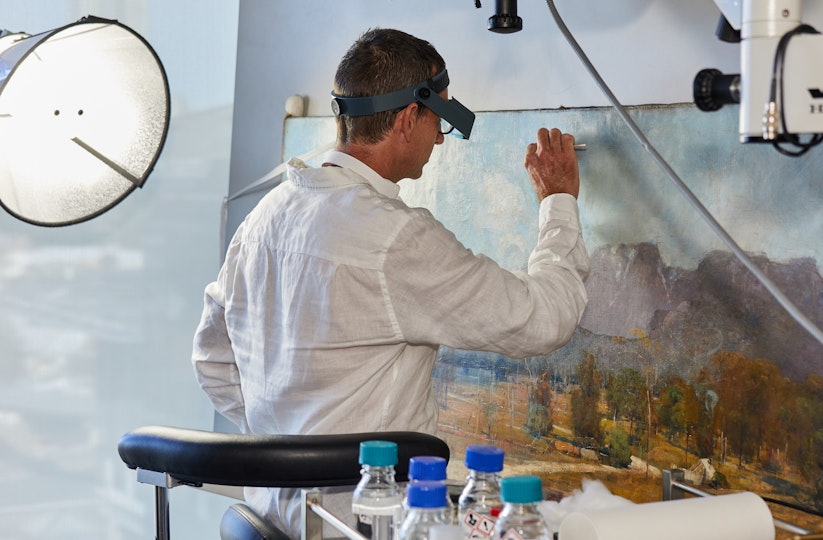 Paintings Conservator Simon Ives working on Arthur Streeton's 1894 painting, The Gloucester Buckets. 