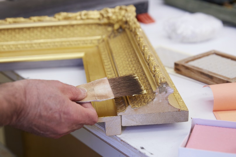 Gold leaf is applied to the frame using traditional gilding techniques. 