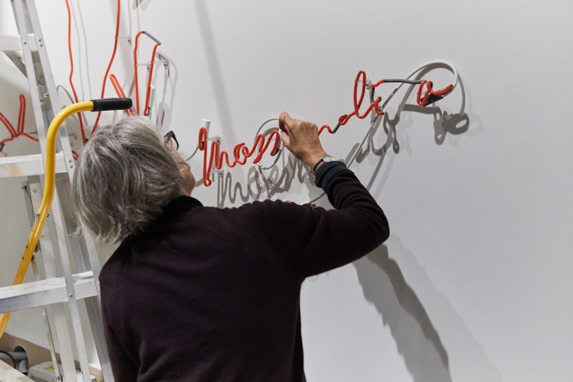 Objects conservator Kerry Head installing Joseph Kosuth’s 2009 neon work The Paradox of Content #4 (Orange) in AGNSW exhibition Some Mysterious Process. 