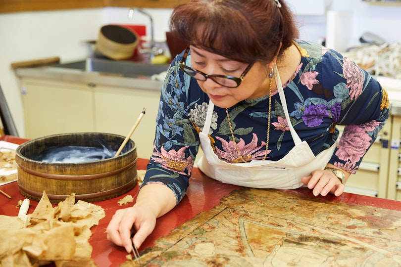 Asian art conservator Lily Yang working on the Gallery’s fragile Yao ceremonial painting Taiwei, the high constable, 1857, for display in Walking with Gods. Conserving nine of these fragile works by Yao people (China) was an intricate process that took six months to complete.