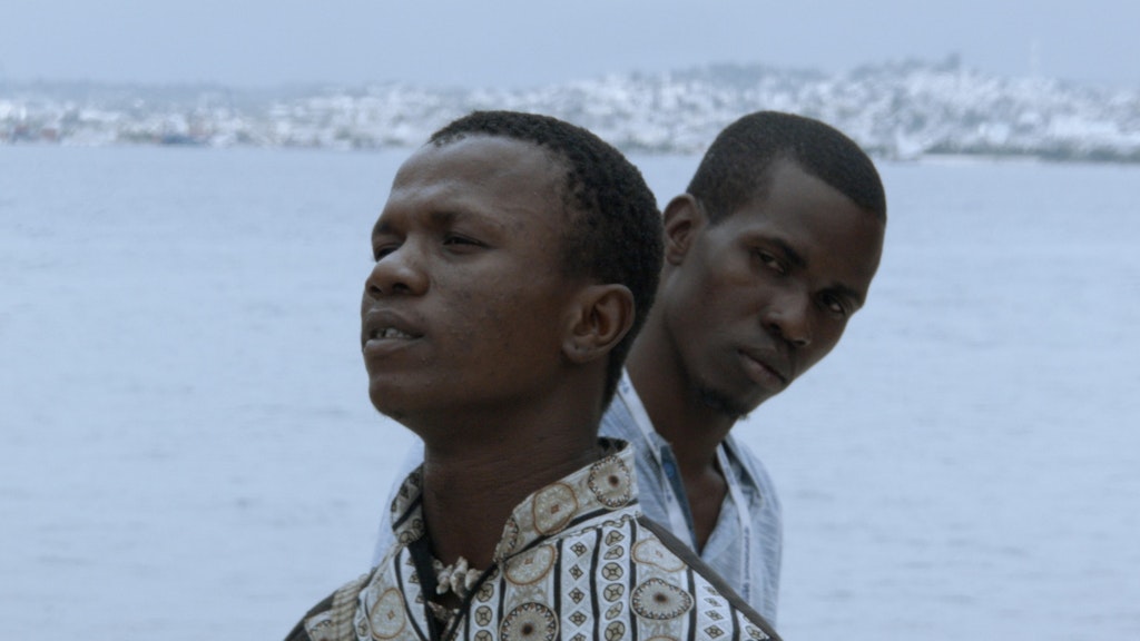 Two dark skin toned people in front of the sea.