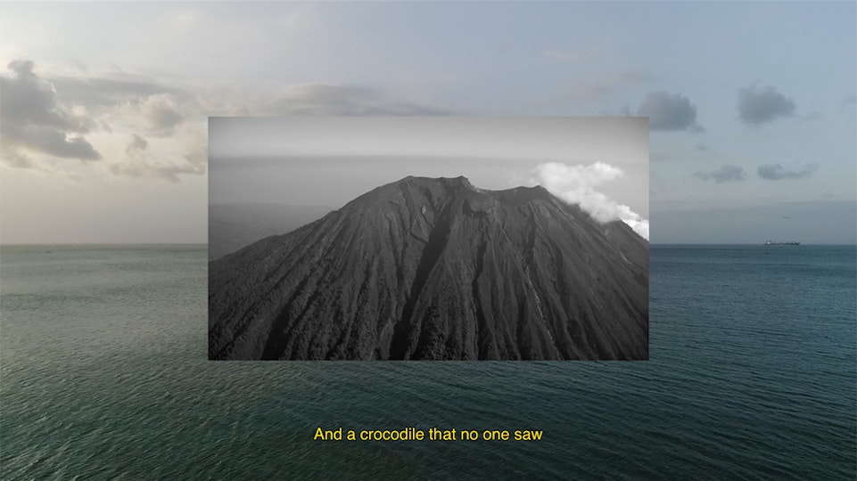 Video still of a volcanic rock peak layered over an image of the sea. A caption at the bottom reads "And a crocodile that no one saw".
