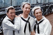 Video still of 3 people in sailor's uniforms on Brooklyn Bridge in New York.