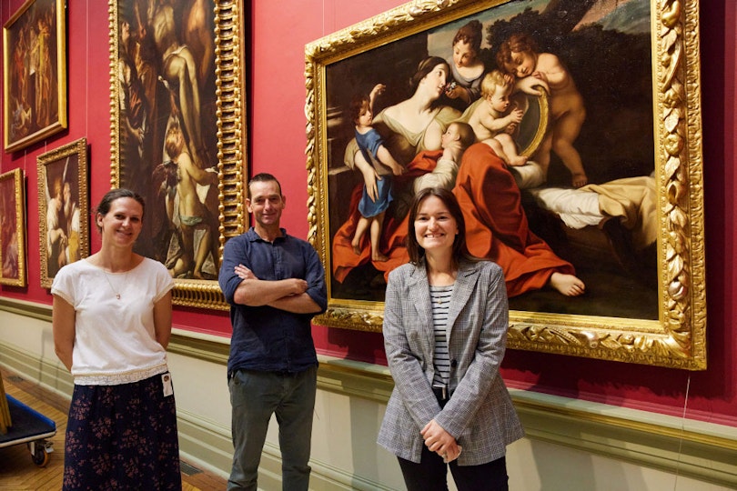 Anne Gerard-Austin (assistant curator, international art), Simon Ives (paintings conservator) and Grace Barrand (frames conservator) with the painting back on display in the grand courts