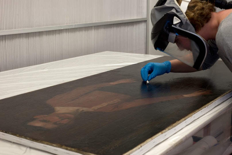 *Removing the top layer of varnish*
It appeared under ultraviolet light that they were at least two layers of varnish on the surface of the painting. The first one which is directly onto the paint film is probably original and, even though it is very patchy, it was decided to leave it. On the other hand, the top one was part of a previous conservation treatment and therefore it was removed. The treatment was undertaken in an extraction booth while wearing a solvent mask and gloves because xylene - the solvent used for this treatment - is toxic.
